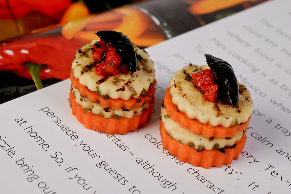 Vegetarian canapes of grilled halloumi and carrot layered with roasted red pepper and black olive