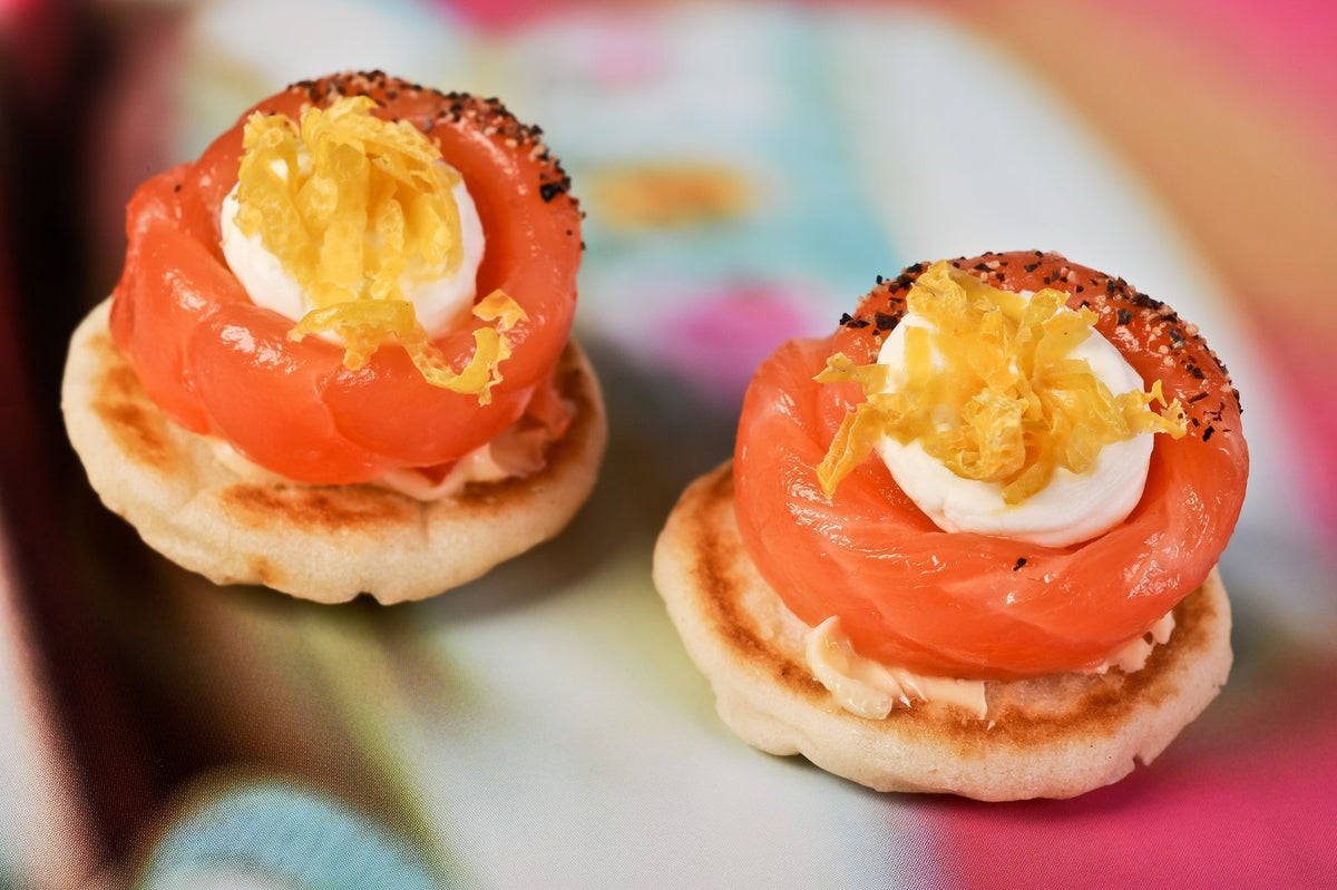 Smoked salmon canapes on crisp blinis with creme fraiche and lemon zest, delivered in London