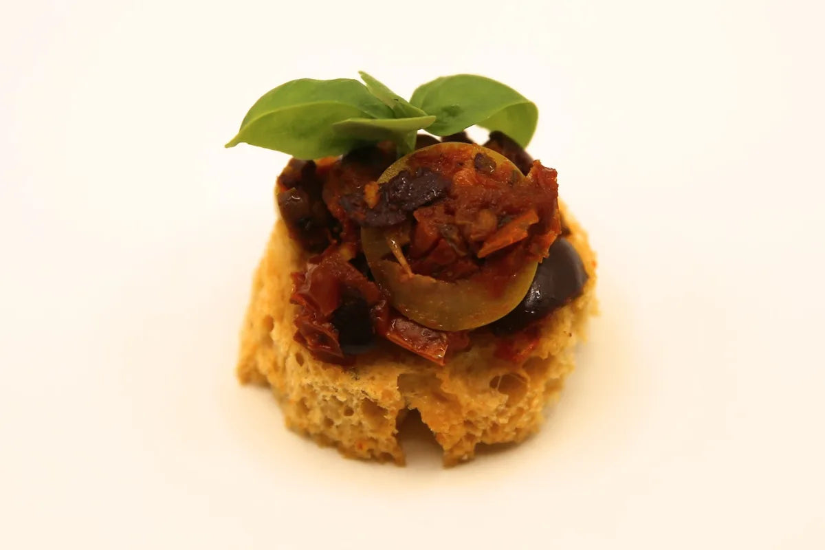 Toasted crostini topped with sun-dried tomato, olives and fresh basil