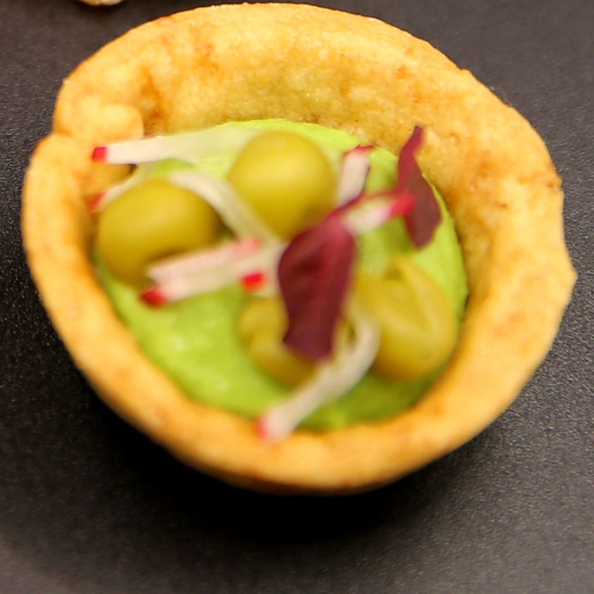 Spiced pea tartlet canapé with minted pea purée, whole peas, radish and micro herbs in a crisp pastry case