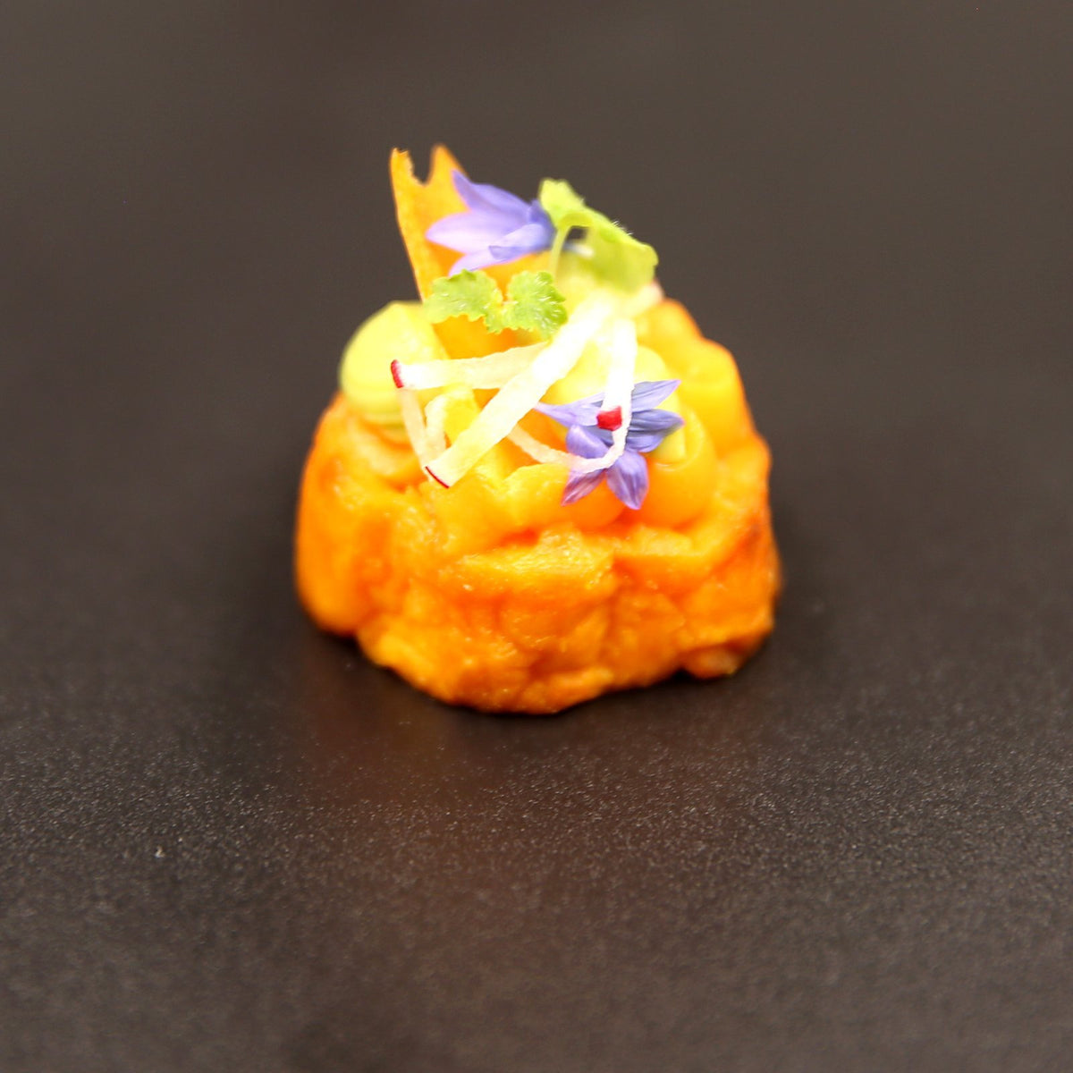 Sweet potato canapé topped with avocado, pomegranate, edible flowers and micro herbs