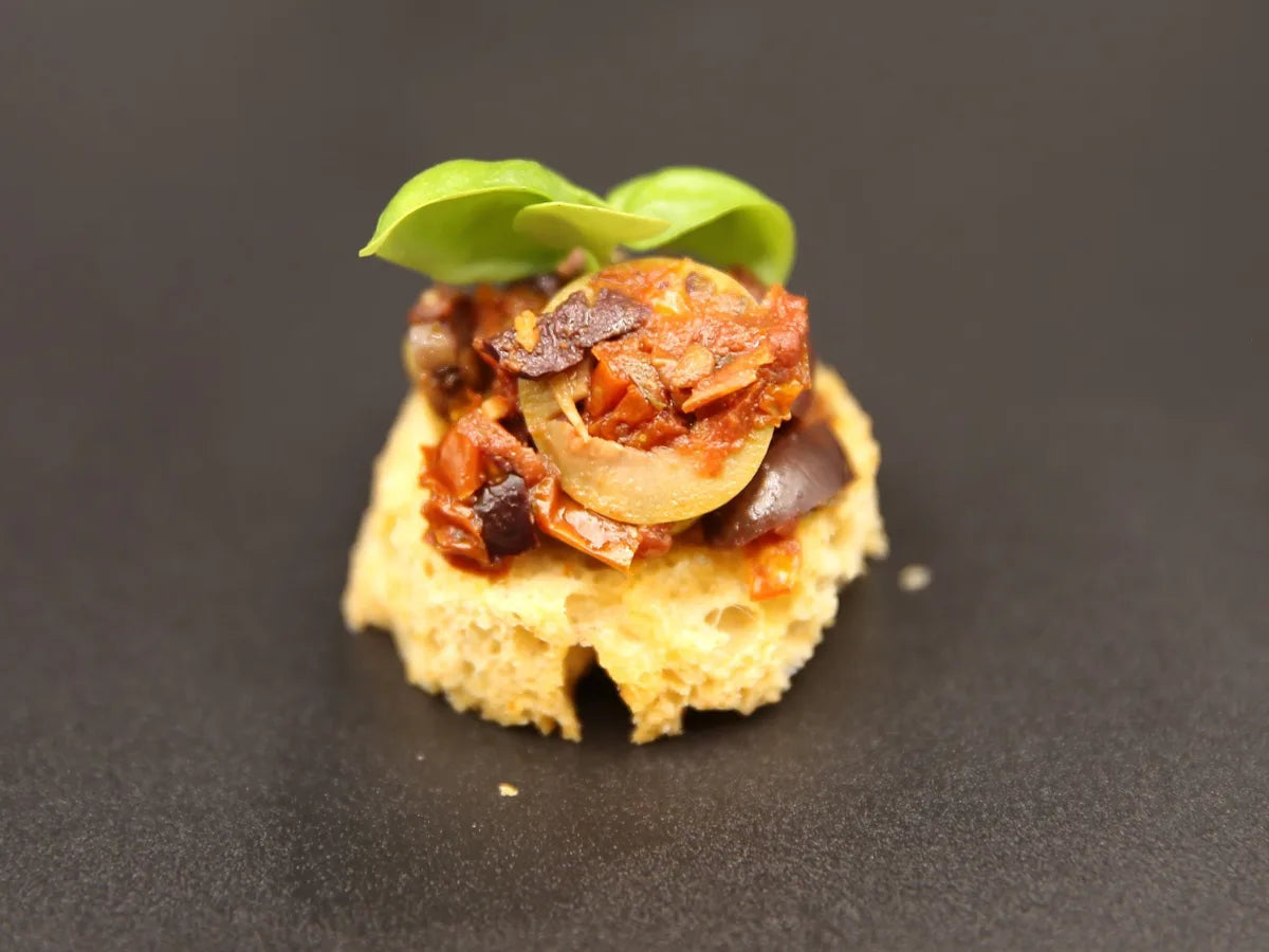 Tomato tapenade canapé with olive and basil on toasted tomato bread